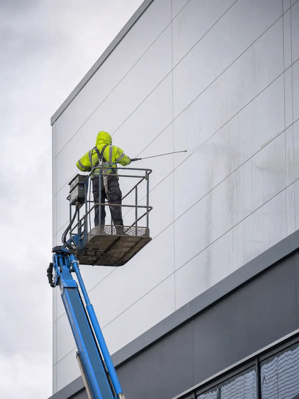 Operative on a boom lift softwashing composite cladding panels